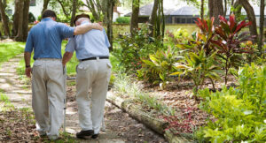 Male carer helps elderly man walking