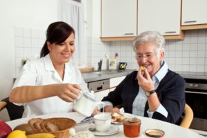 carer helps elderly woman at breakfast